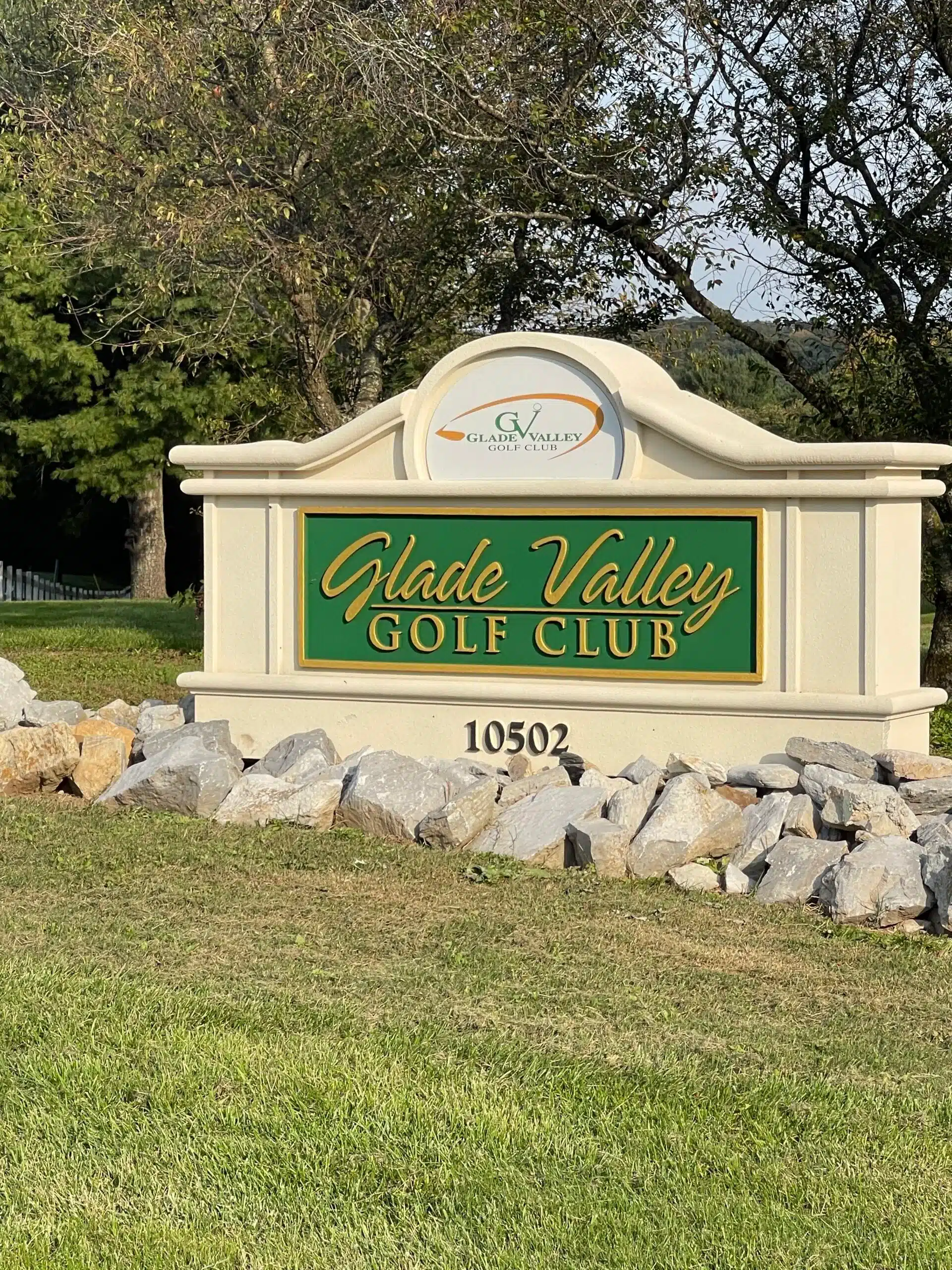 a Stone Sign with a Green and Gold Plaque Reads Glade Valley Golf Club 10502 the Clubs Logo Tops It Surrounded by Rocks Grass and Leafy Trees Under a Blue Md Sky Its One of the Scenic Golf Courses Near Frederick