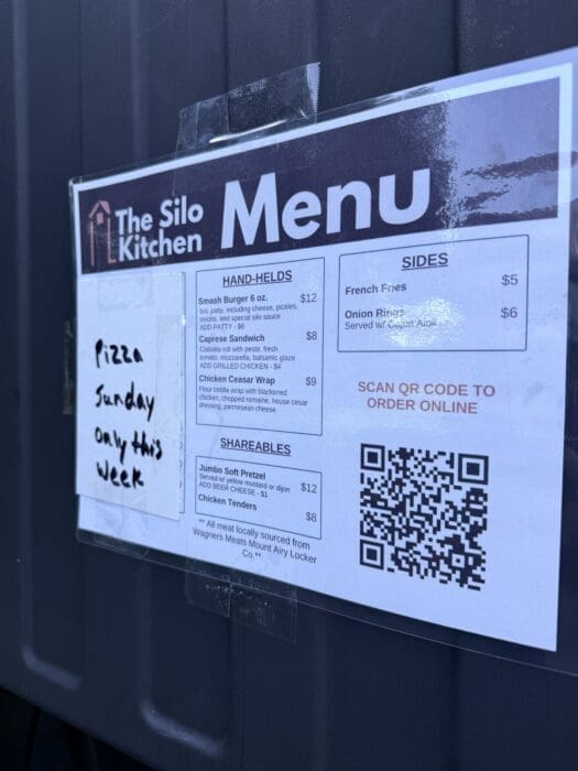 Menu sign on dark wall reading 'The Silo Kitchen' with large 'Menu' title and a QR code on the right side.